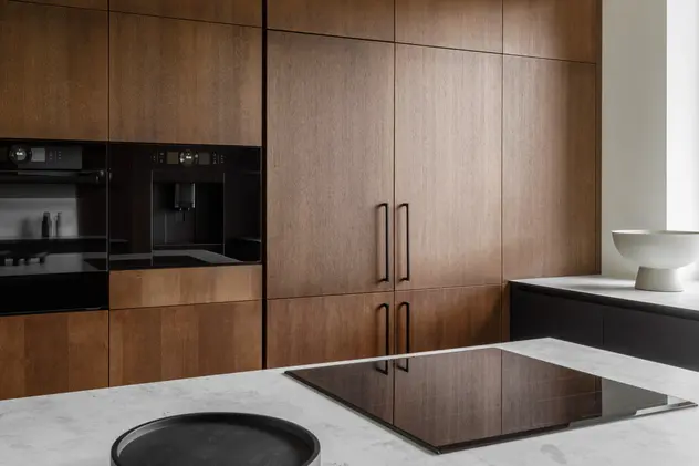 Kuchnia w kolorze brązowym z drewnianymi frontami, styl minimalistyczny. Element charakterystyczny: drewniane fronty