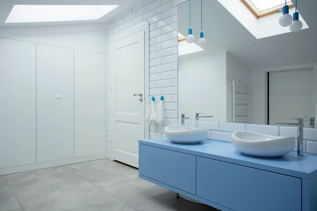 Łazienka w kolorze białym z niebieską szafką, styl skandynawski. Element charakterystyczny: niebieska szafka