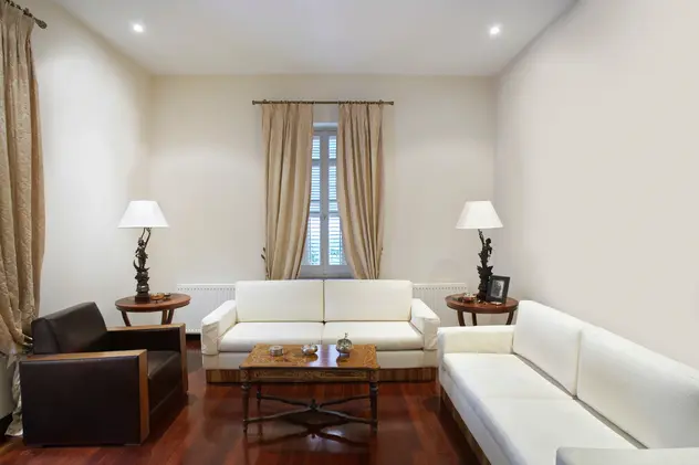 Salon w kolorze białym z jasną kanapą w stylu kolonialnym, styl kolonialny. Element charakterystyczny: jasna kanapa w stylu kolonialnym