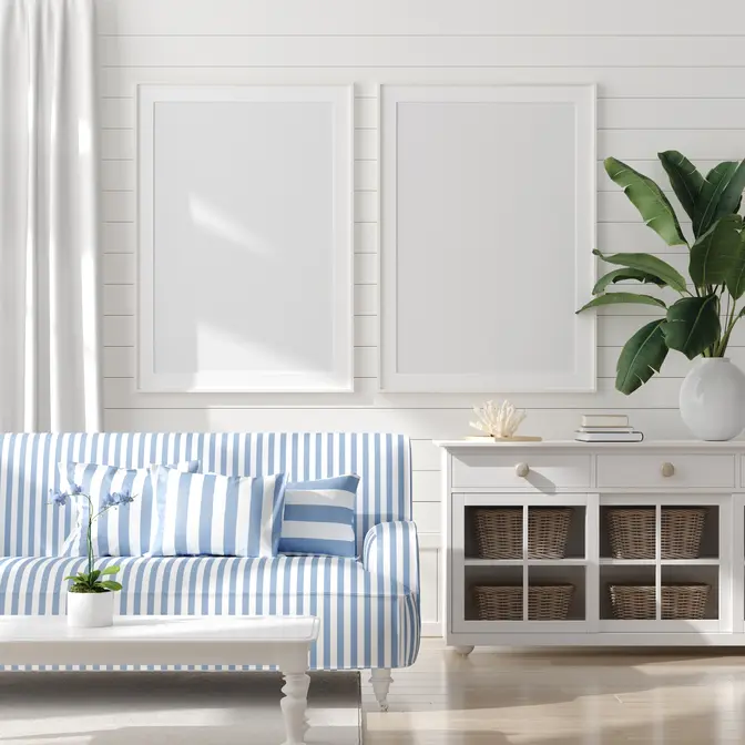 Salon w kolorze białym z kanapą w niebieskie paski, styl marynistyczny. Element charakterystyczny: kanapa w niebieskie paski