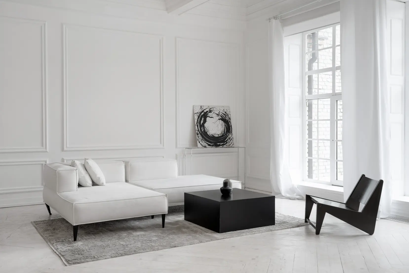 Salon w kolorze białym z białą kanapą, styl minimalistyczny. Element charakterystyczny: biała kanapa