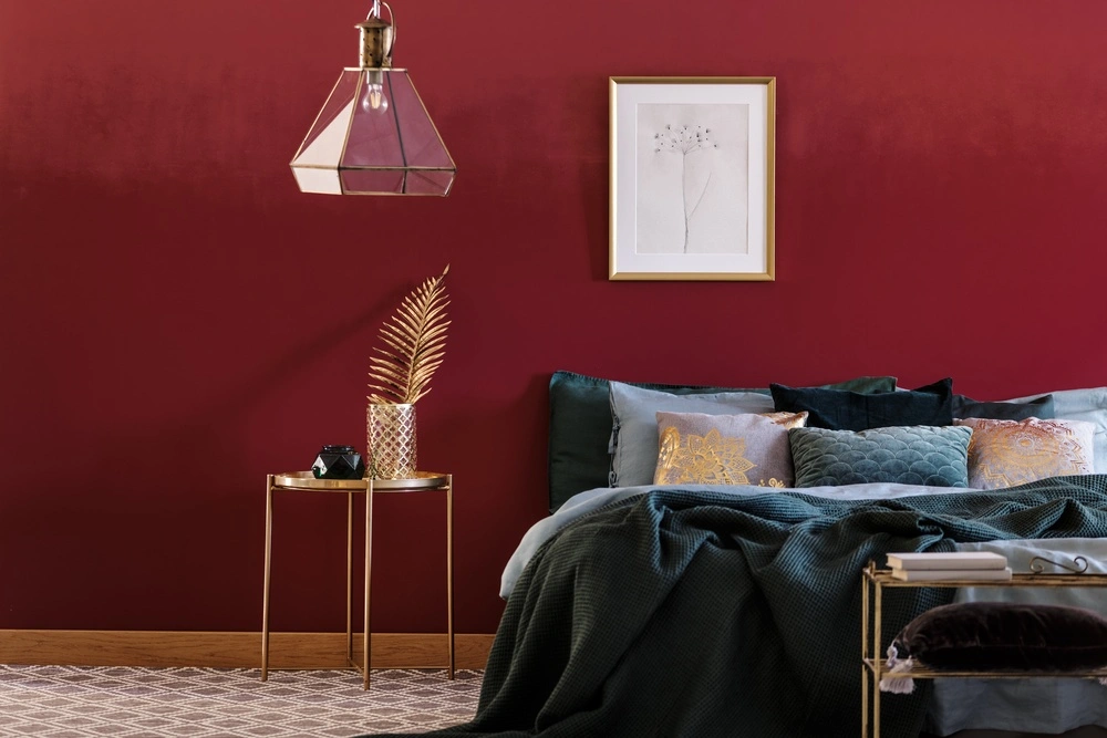 Sypialnia w stylu glamour z czerwoną ścianą. Kolory uzupełniające: czerwony, bordowy, złoty