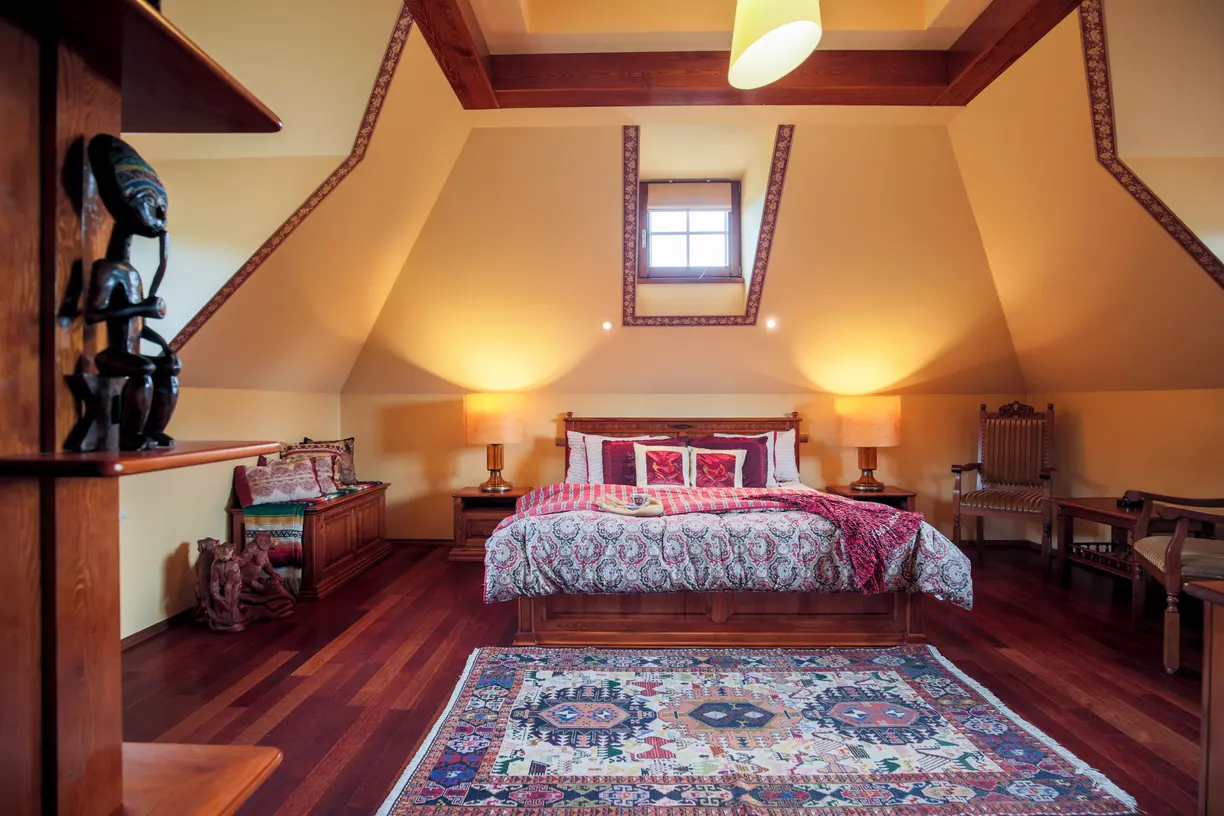 Sypialnia w kolorze beżowym z kolorowym dywanem, styl kolonialny. Element charakterystyczny: kolorowy dywan