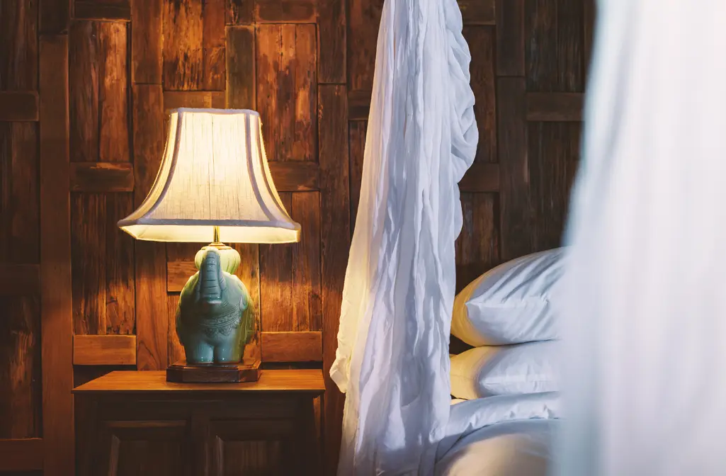 Sypialnia w kolorze brązowym z lampką nocną w stylu kolonialnym, styl kolonialny. Element charakterystyczny: lampka nocna w stylu kolonialnym