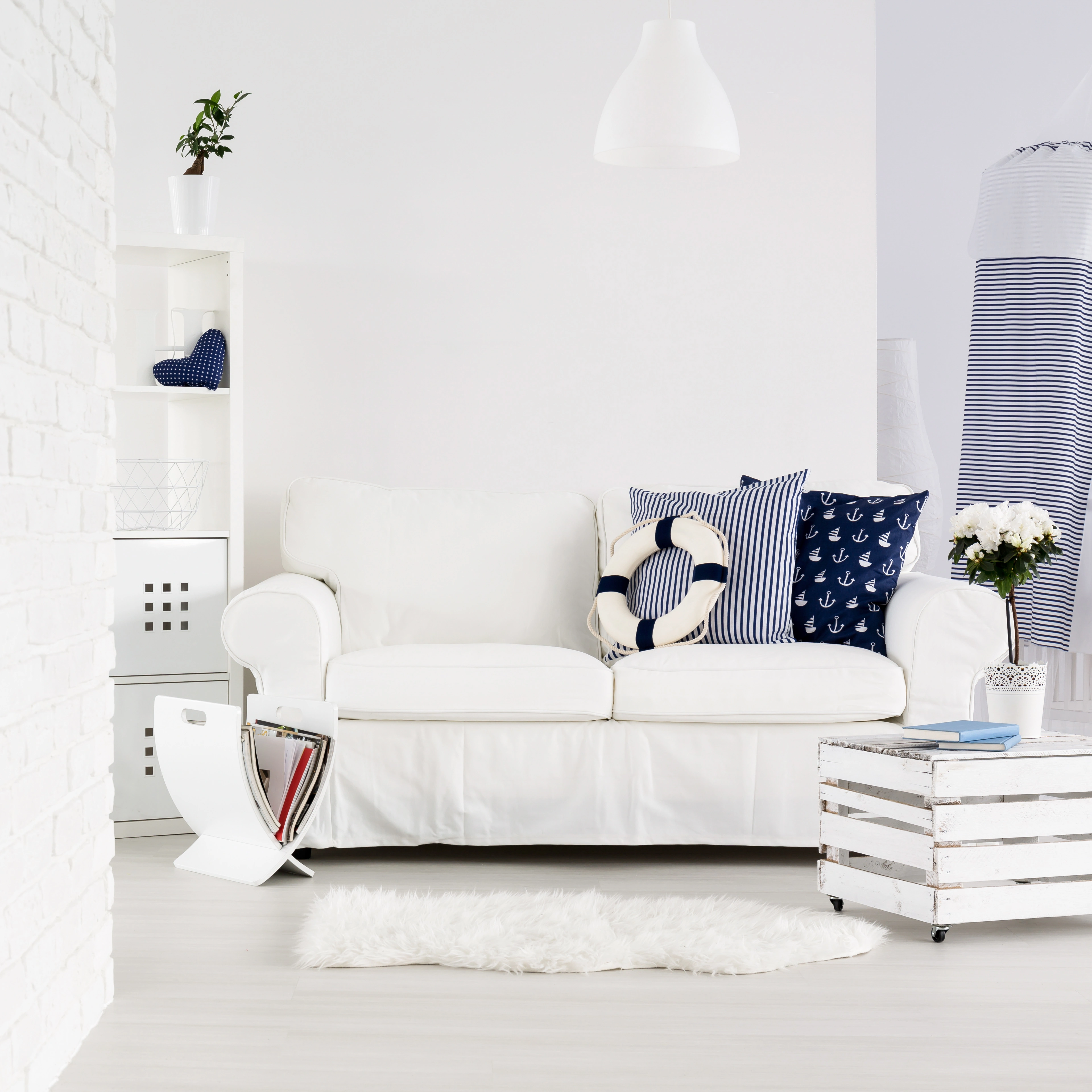 Inspiracja prezentująca salon w kolorze białym z białą kanapą i morskimi dodatkami, styl marynistyczny. Element charakterystyczny: biala kanapa z morskimi dodatkami