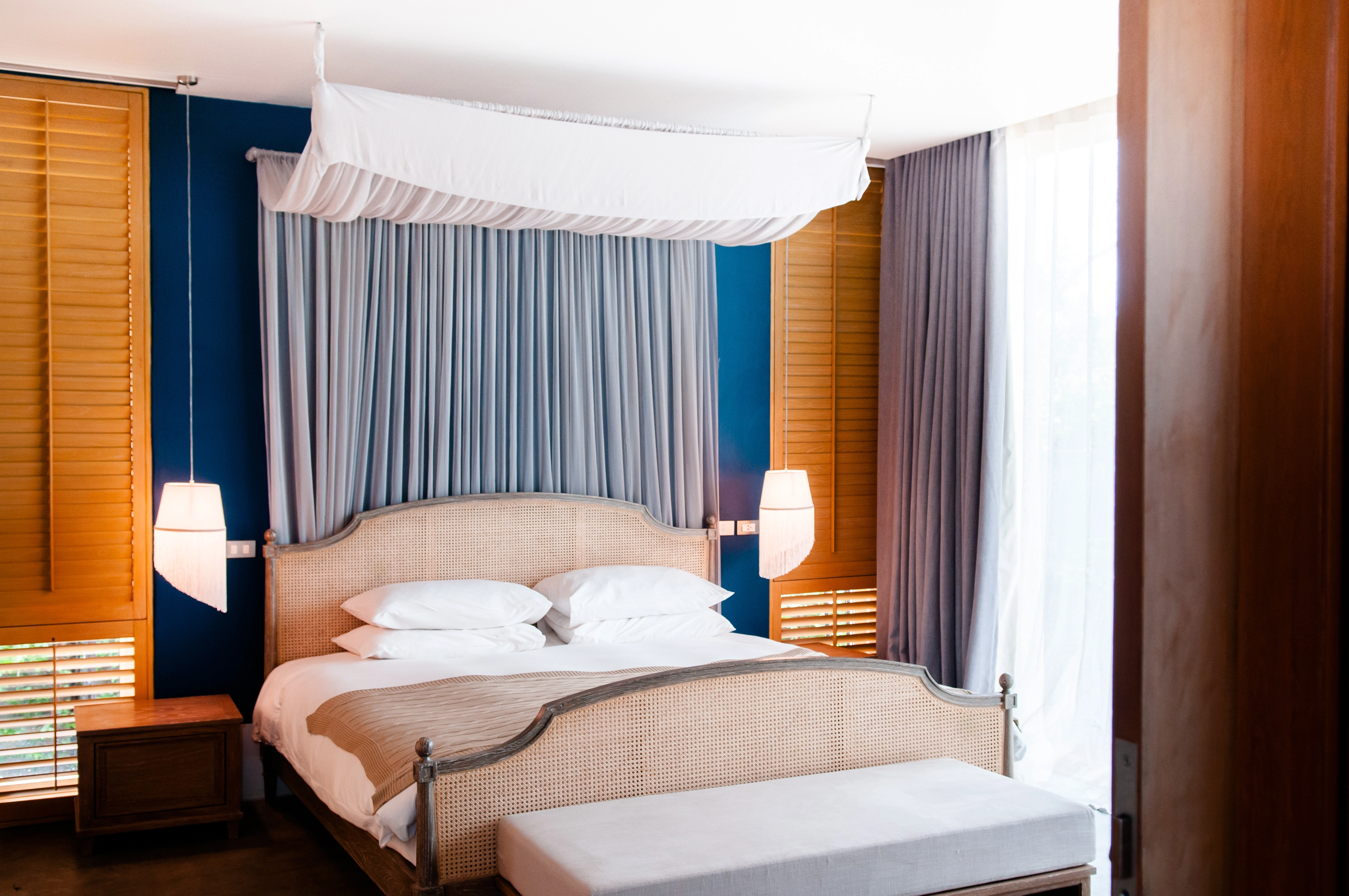 Inspiracja prezentująca sypialnię w kolorze brązowym z łóżkiem z baldachimem, styl kolonialny. Element charakterystyczny: łóżko z baldachimem