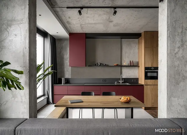 Otwaty salon z kuchnią w stylu loftowym. Kuchnia w kolorze ciemnofioletowym z drewnianymi elementami.