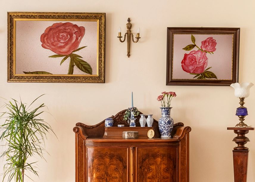 Salon w stylu angielskim z komodą i obrazami z motywem róż.