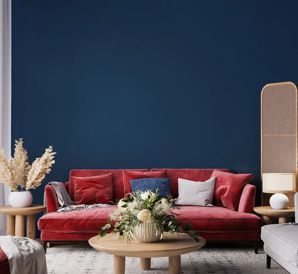 Salon w stylu boho z czerwoną kanapą i beżowym i niebieskim jako kolory uzupełniające.