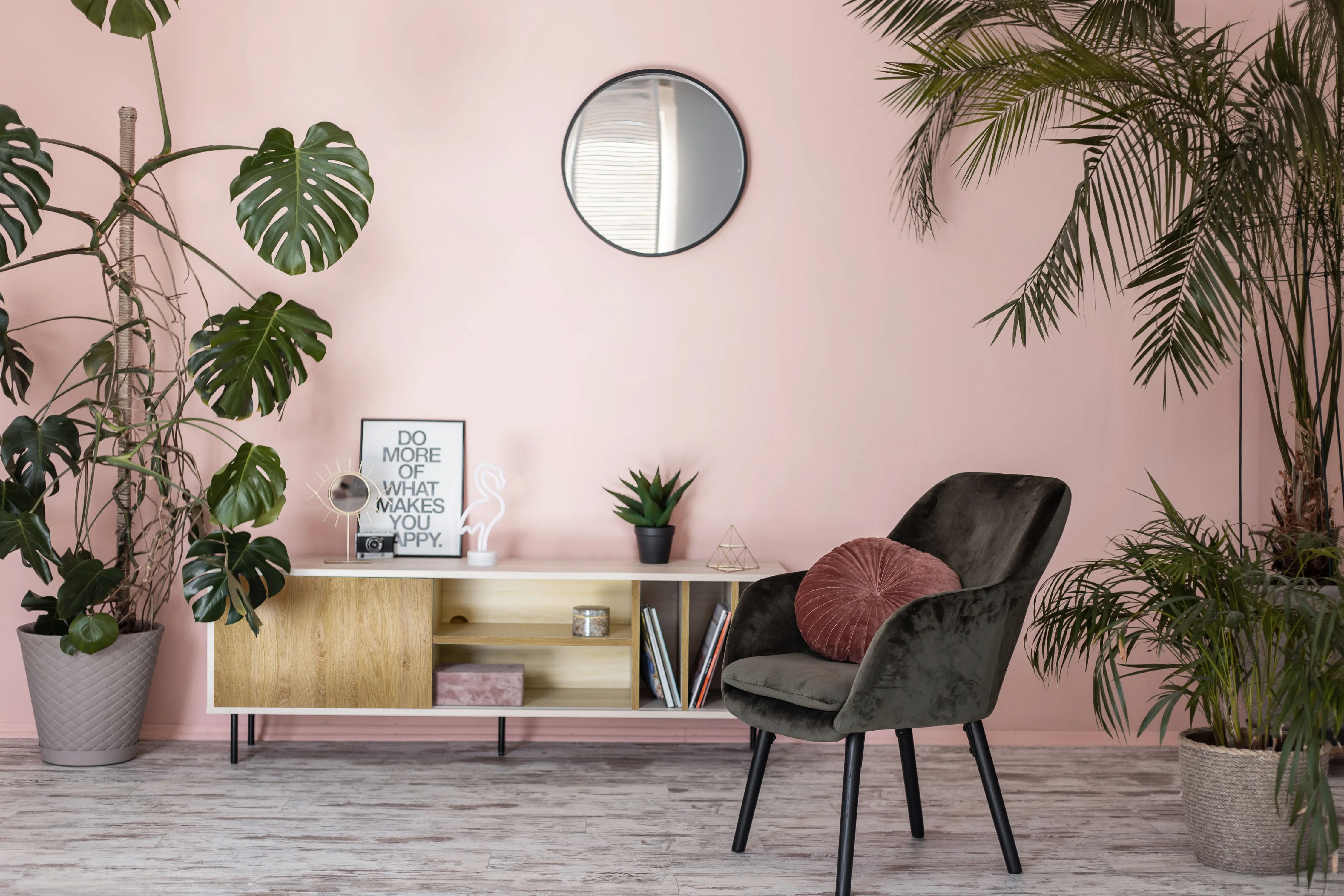 Salon w kolorze różowym w stylu vintage z komodą i zielonym fotelem.