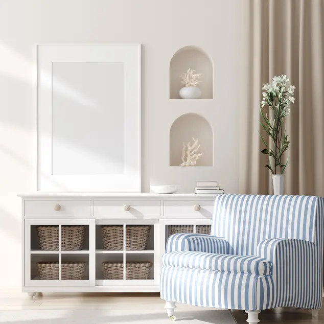 Salon w stylu hampton z białymi ścianami i duzym fotelem w biało-niebieskie paski