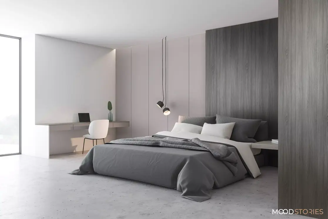 Sypialnia w stylu minimalistycznym z dużym, prostym łóżkiem. Kolory dominujące widoczne na zdjęciu to biały i szary.